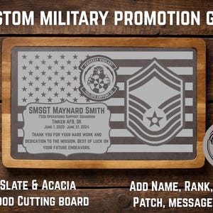 May include: A rectangular slate and acacia wood cutting board, 13" x 9", with a military promotion design. The design includes an American flag, a military emblem, and a rank insignia. Text includes a name, unit, and dates.