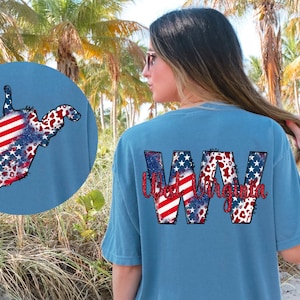 May include: A blue t-shirt with a red, white, and blue West Virginia state outline and the text "West Virginia" in a red, white, and blue font.