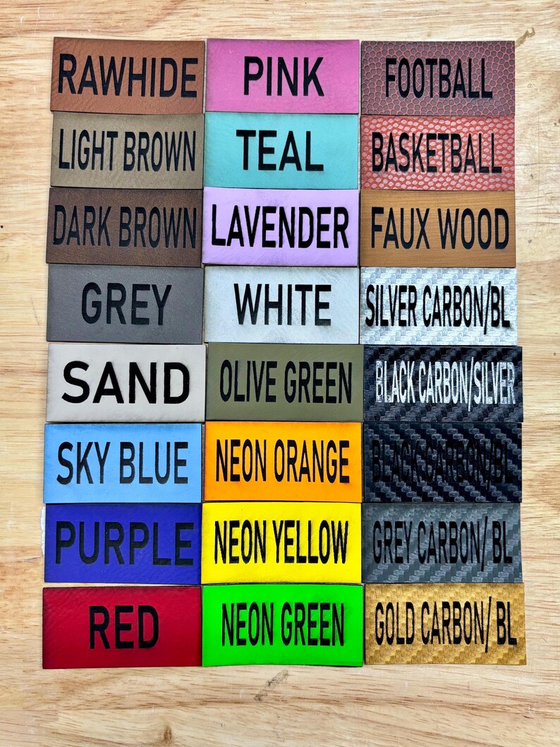 May include: A collection of 18 leather and fabric swatches with color and texture names printed on each. The swatches include colors like rawhide, pink, teal, lavender, white, olive green, sky blue, neon orange, purple, neon yellow, red, and neon green.  The swatches also include textures like football, basketball, faux wood, silver carbon, black carbon, and grey carbon.