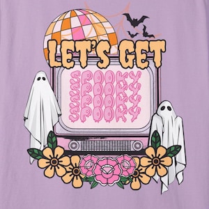 May include: Purple t-shirt with a retro TV screen graphic that says "Let's Get Spooky" with ghosts and flowers on either side.