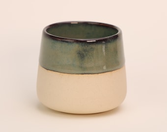 May include: A ceramic mug with a white base and a green and brown glaze.