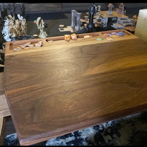 May include: A wooden game board with compartments for dice and game pieces. The board is made of dark wood with a smooth finish.