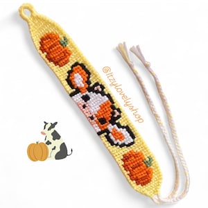May include: A yellow friendship bracelet with a cow and pumpkin design. The bracelet features a repeating pattern of orange pumpkins and a black, white, and orange cow. The text "@itzylovelyshop" is visible on the bracelet.