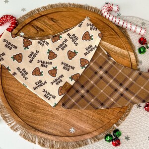 May include: Two dog bandanas, one with a brown plaid pattern and the other with a beige background and a repeated pattern of brown poop with a green sprig and the text "Bah Humbug".