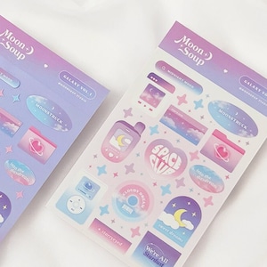 May include: Two sheets of stickers with a space and galaxy theme. The stickers are on a white background and feature illustrations of planets, stars, clouds, and moons. The text on the stickers reads "Galaxy Vol. 1", "Moonstruck", "Space Club", "Cloudy Dreams", "We're All Stardust", and "Galaxy Vol. 2".