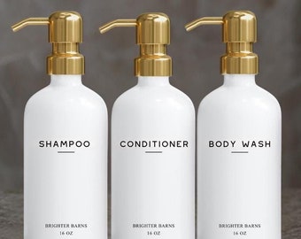 May include: Three white pump bottles with gold tops and labels. The bottles are labeled "Shampoo", "Conditioner", and "Body Wash". Each bottle has the text "Brighter Barns 16 oz" printed on the bottom.