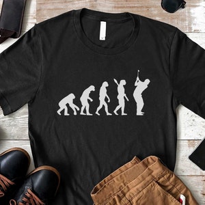 May include: Black t-shirt with a white graphic of the evolution of man, ending with a golfer swinging a club.
