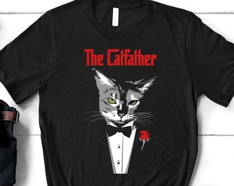 Könnte beinhalten: Schwarzes T-Shirt mit einem Aufdruck eines Kätzchens im Smoking mit einer roten Rose. Der Text "The Catfather" ist in Rot über dem Kätzchen gedruckt.