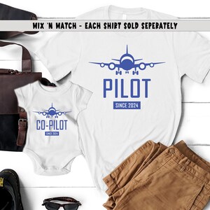 May include: Two white t-shirts with blue airplane graphics and text. The larger shirt says "PILOT SINCE 2024" and the smaller shirt says "CO-PILOT SINCE 2024".
