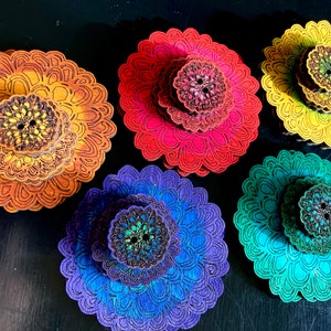 May include: Five wooden mandala-style ornaments in a rainbow gradient of colors. The ornaments are layered and have a 3D effect. The colors are yellow, orange, red, blue, and green.