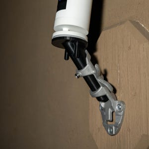 Op de afbeelding: Een witte beveiligingscamera gemonteerd op een verstelbare beugel in zwart en zilver. De beugel is bevestigd aan een houten oppervlak. De camera is naar beneden gericht en biedt zicht op het gebied eronder.