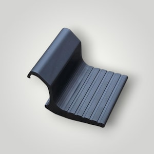 May include: A matte black plastic component featuring a curved hook-shaped top section and a flat, rectangular base with a series of parallel, raised ridges running across the surface, designed for secure placement or attachment.