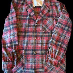 May include: A vintage red, black, and gray plaid jacket with a notched collar, two front pockets, and button closures. The jacket has long sleeves with buttoned cuffs and a white lining at the collar.