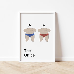 May include: A white framed print with a black and white illustration of two sumo wrestlers. The wrestlers are wearing blue and red loincloths. The text "The Office" is printed below the illustration.