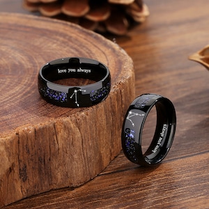 May include: Two black tungsten carbide rings with a constellation design and the inscription "love you always".