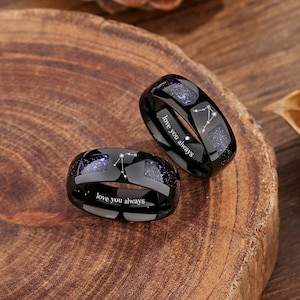 May include: Two black tungsten carbide rings with a constellation design and the inscription "love you always".