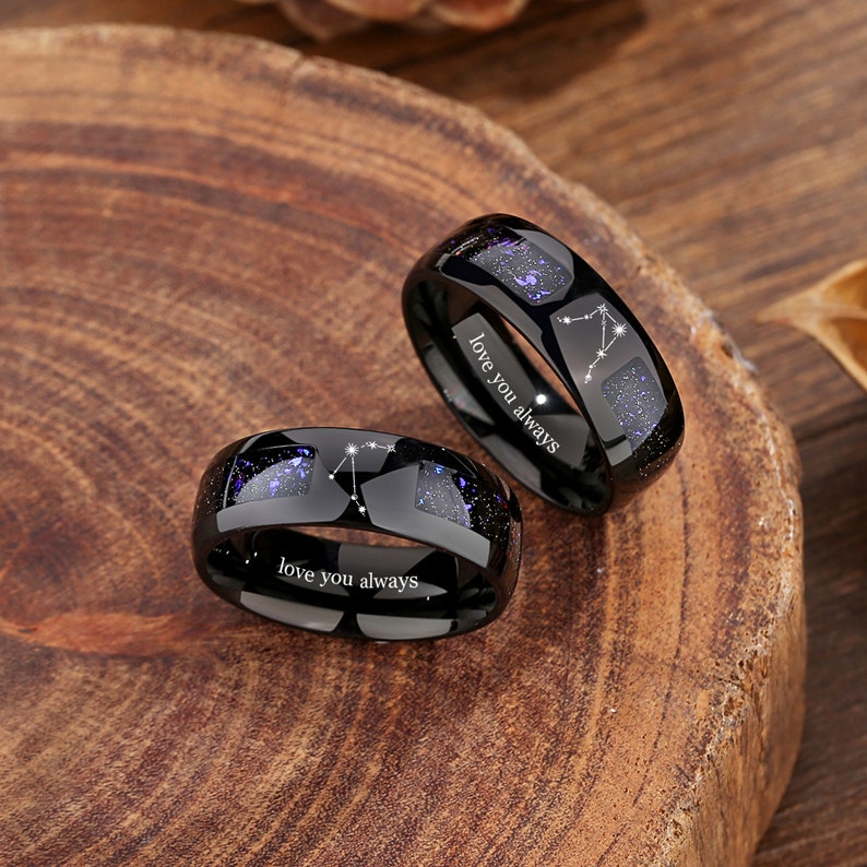 May include: Two black tungsten carbide rings with a constellation design and the inscription "love you always".