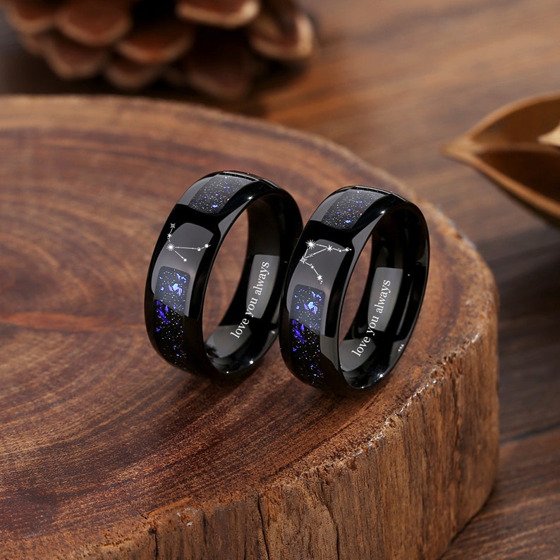 May include: Two black tungsten carbide rings with a blue starry sky design and the inscription "love you always".