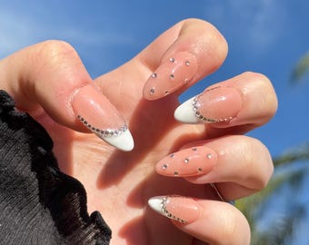 Unghie finte per Capodanno con strass e glitter, punta francese bianca glamour
