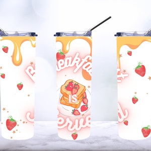 May include: A white stainless steel tumbler with a pink and yellow design. The tumbler features a graphic of a plate of french toast with strawberries and the text "Breakfast is Served". The tumbler is decorated with a pattern of small stars and strawberries.