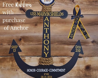 May include: A navy blue anchor-shaped wooden plaque with gold lettering and a rope accent. The plaque includes the text "USS MARVIN SHIELDS" and "ANTHONY". A yellow and navy blue ribbon is also present. The text "HONOR COURAGE COMMITMENT" is displayed.