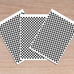 May include: Three sheets of black and white chequered paper. The sheets are arranged in a triangular shape.