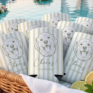 Könnte beinhalten: Ein Weidenkorb gefüllt mit hellgrün-weiß gestreiften Getränkekühlern, die eine Strichzeichnung eines Golden Retrievers und den Text Cheers! Love, Winston zeigen. Frische Zitronenscheiben und Minzblätter liegen im Korb.