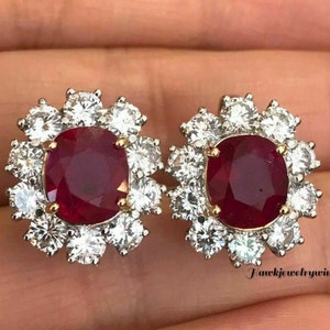 Peut inclure: Une paire de boucles d'oreilles en rubis et diamants. Chaque boucle d'oreille présente un gros rubis de forme ovale entouré d'un halo de diamants plus petits.