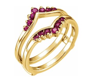 May include: A yellow gold ring guard featuring a chevron-shaped design adorned with ten round-cut, deep pinkish-red rubies. The band has a polished finish and is structured to frame another ring, showcasing a V-shaped contour set with gemstones.