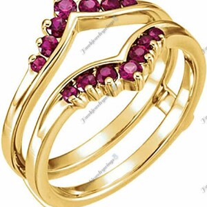 May include: A gold ring setting with a V-shaped design, accented with a row of ruby stones. The setting is designed to hold a center stone.