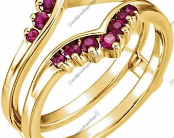 May include: A gold ring setting with a V-shaped design, accented with a row of ruby stones. The setting is designed to hold a center stone.