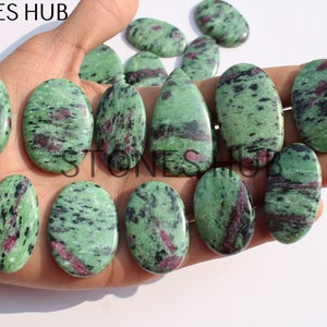 May include: A selection of oval and teardrop-shaped zoisite stones with ruby inclusions. The stones are green with black and red markings. The image includes the text "STONES HUB".
