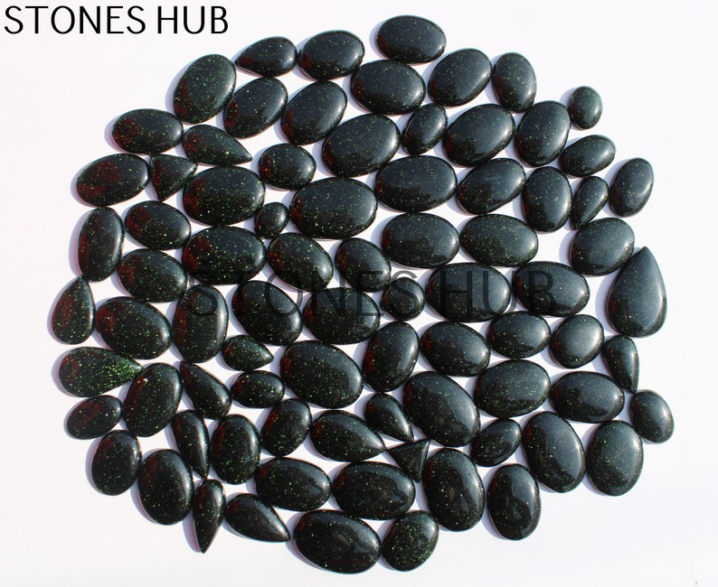 May include: A collection of 50 green aventurine gemstone cabochons in various sizes and shapes. The stones have a sparkly, glittery appearance.