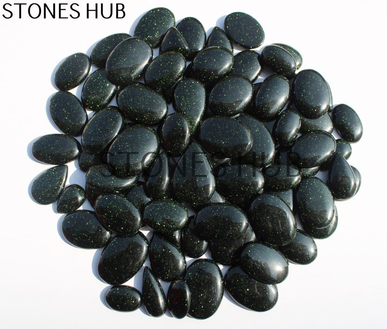 May include: A large group of dark green, oval-shaped, sparkly stones. The stones have a glittery, speckled appearance.