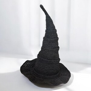May include: A black crocheted witch hat with a tall, pointed crown and a wide brim.