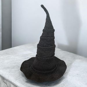 May include: A black crocheted witch hat with a tall, pointed crown and a wide brim.