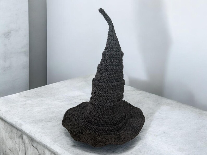 May include: A black crocheted witch hat with a tall, pointed crown and a wide brim.