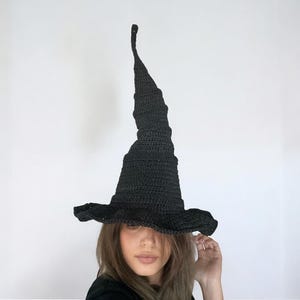 May include: A black crocheted witch hat with a tall pointed crown and a wide brim.