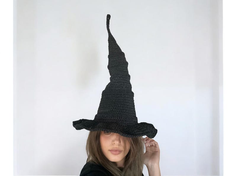 May include: A black crocheted witch hat with a tall pointed crown and a wide brim.