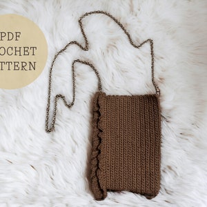 May include: A brown crocheted bag with a silver chain strap. The bag is on a white fluffy surface. The text "PDF CROCHET PATTERN" is on a yellow circle in the top left corner of the image.