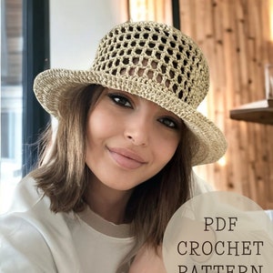 Puede incluir: Un patrón de sombrero de crochet en formato PDF. El sombrero es beige y tiene un ala ancha. El patrón es para un sombrero de crochet con tejido abierto.