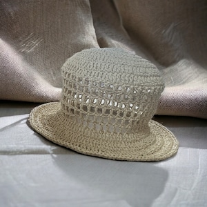 May include: A crocheted straw hat with a wide brim and a light beige color.