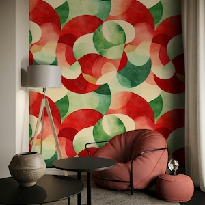 May include: A modern living room with a red armchair, a small side table, and a floor lamp. The focal point is a wall covered in a colorful abstract pattern of red, green, and cream-colored shapes. A round black table and a decorative vase are in the foreground.
