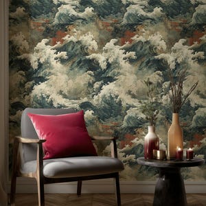 Op de afbeelding: Interieur met een grijze fauteuil en een rood fluwelen kussen. Het behang toont een groot golfpatroon in blauw, wit en beige. Een kleine ronde tafel toont vazen, kaarsen en decoratieve items.