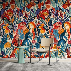 May include: A colourful botanical wallpaper with stylized flowers, leaves, and female figures in red, orange, blue, and purple. A light wood chair and a small, round, teal side table with a decorative vase are in front of the wallpaper.