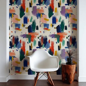 Puede incluir: Papel pintado de arte abstracto con pinceladas coloridas en tonos rojos, azules, verdes, morados y amarillos sobre un fondo crema. Una silla blanca con patas de madera y una pequeña mesa auxiliar de madera con una planta.