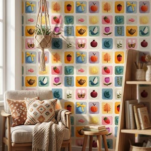 May include: A colorful wallpaper featuring a repeating pattern of square blocks with various illustrations. The blocks showcase images of fruits, flowers, insects, and teapots in a whimsical style. A chair with pillows and a plant in a macrame hanger are in the foreground.