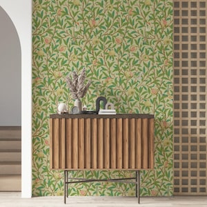 May include: A room featuring a wooden cabinet with a ribbed front, a beige and green floral wallpaper, and a decorative wooden screen. The wallpaper has a pattern of green leaves and red and yellow fruit.