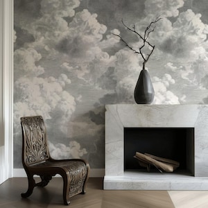 May include: A room featuring a cloud-patterned wallpaper in shades of gray and white. A dark wooden chair with ornate carvings sits in front of the wall. A marble fireplace with a dark vase and branches is also present.