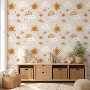 May include: Wallpaper featuring a repeating pattern of smiling suns, rainbows with clouds, planets with rings, and small stars in shades of tan, brown, and white. The design is printed on a light beige background, creating a cohesive celestial theme.